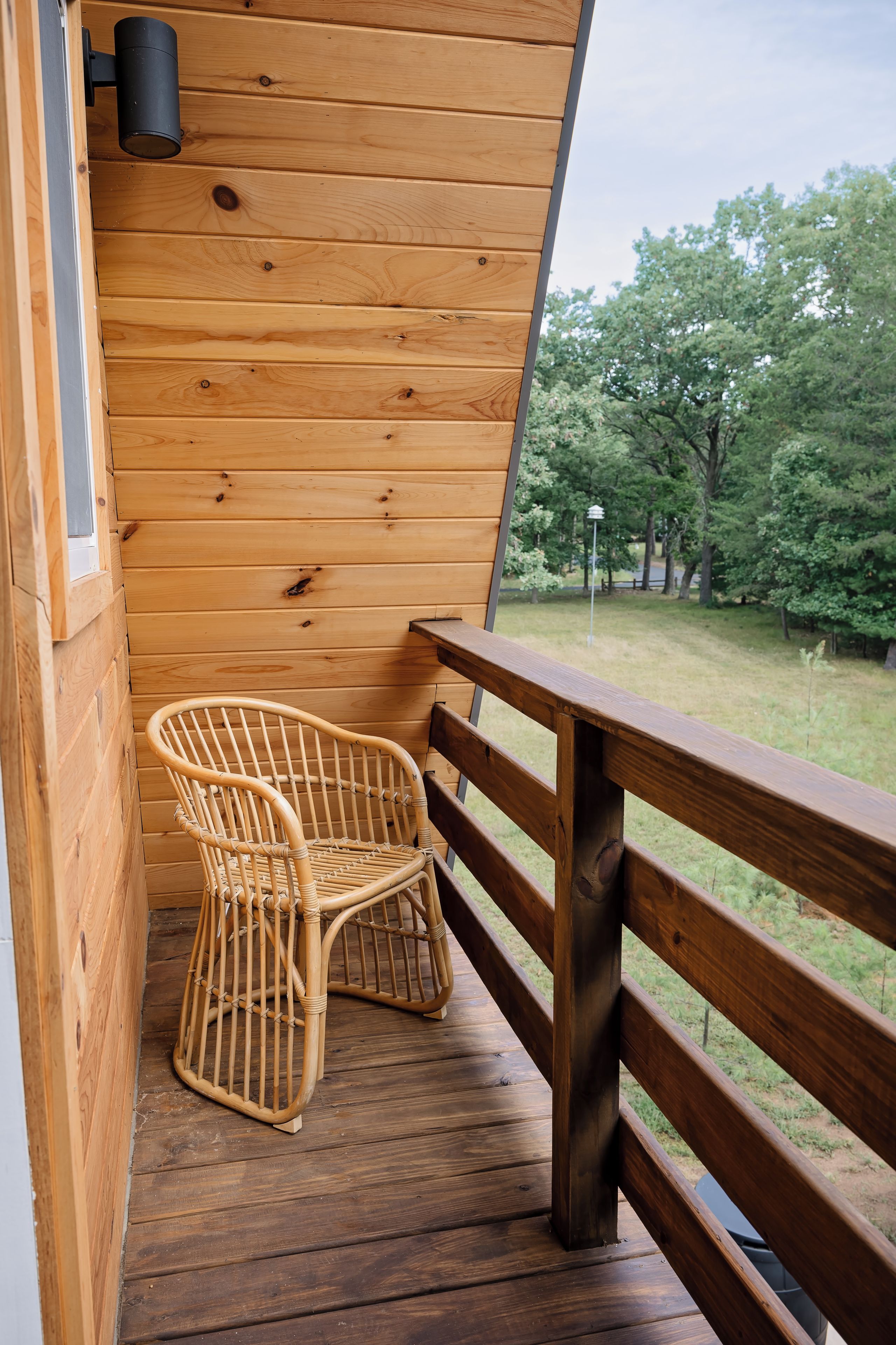 A wooden deck with two wicker chairs and a railing.