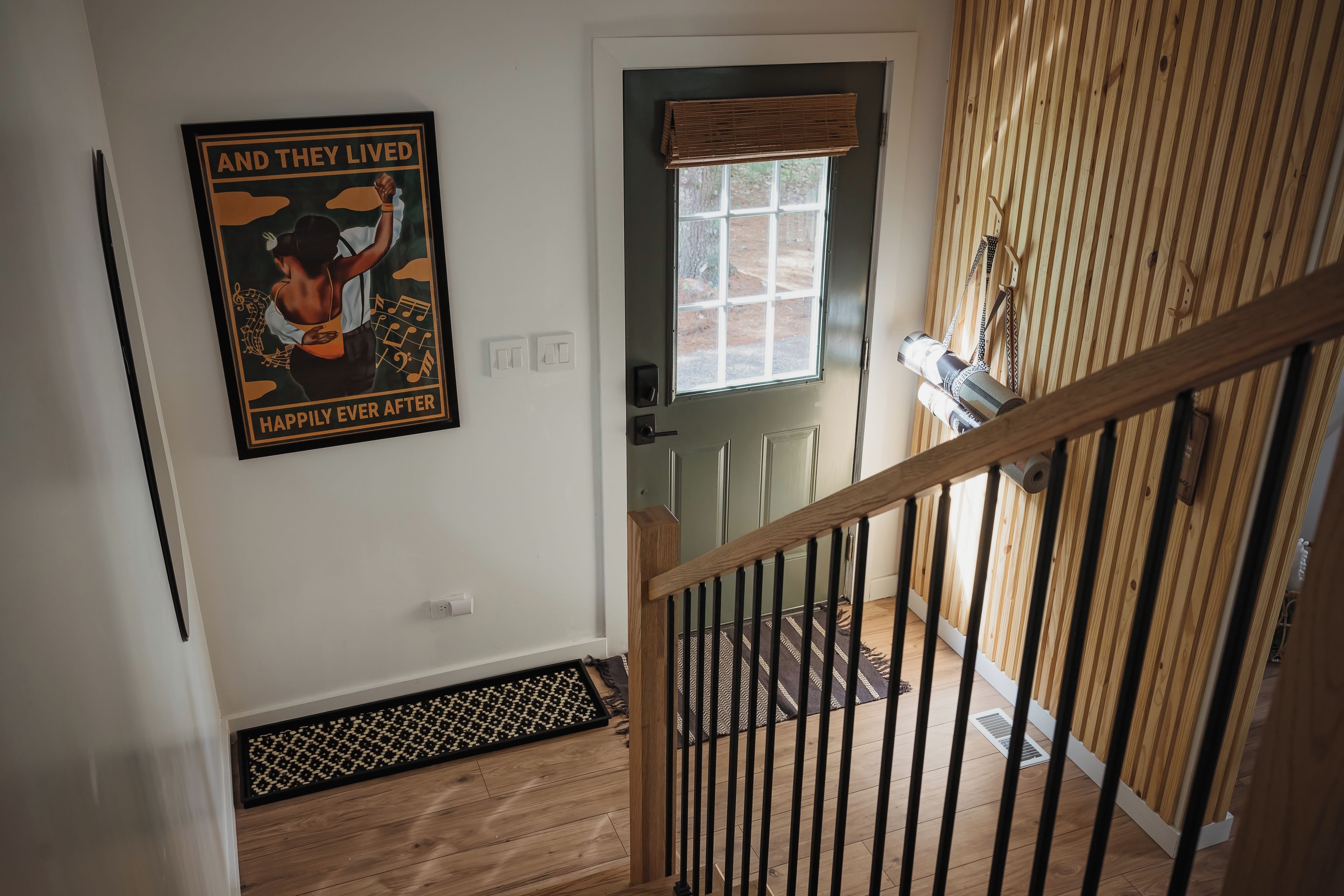 Una escalera con barandilla de madera, una puerta con ventana y un cartel en la pared.