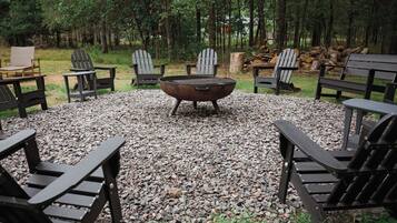 Un área de estar al aire libre con sillas Adirondack y un brasero rodeado de grava.