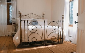 Una stanza con un letto dalla struttura in metallo, biancheria da letto bianca e una finestra con tende.
