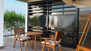 Une terrasse extérieure avec une table et des chaises, une balançoire et une vue sur le ciel.
