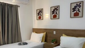 Une chambre d’hôtel avec deux lits, une table de chevet, une plante en pot et un climatiseur fixé au mur.