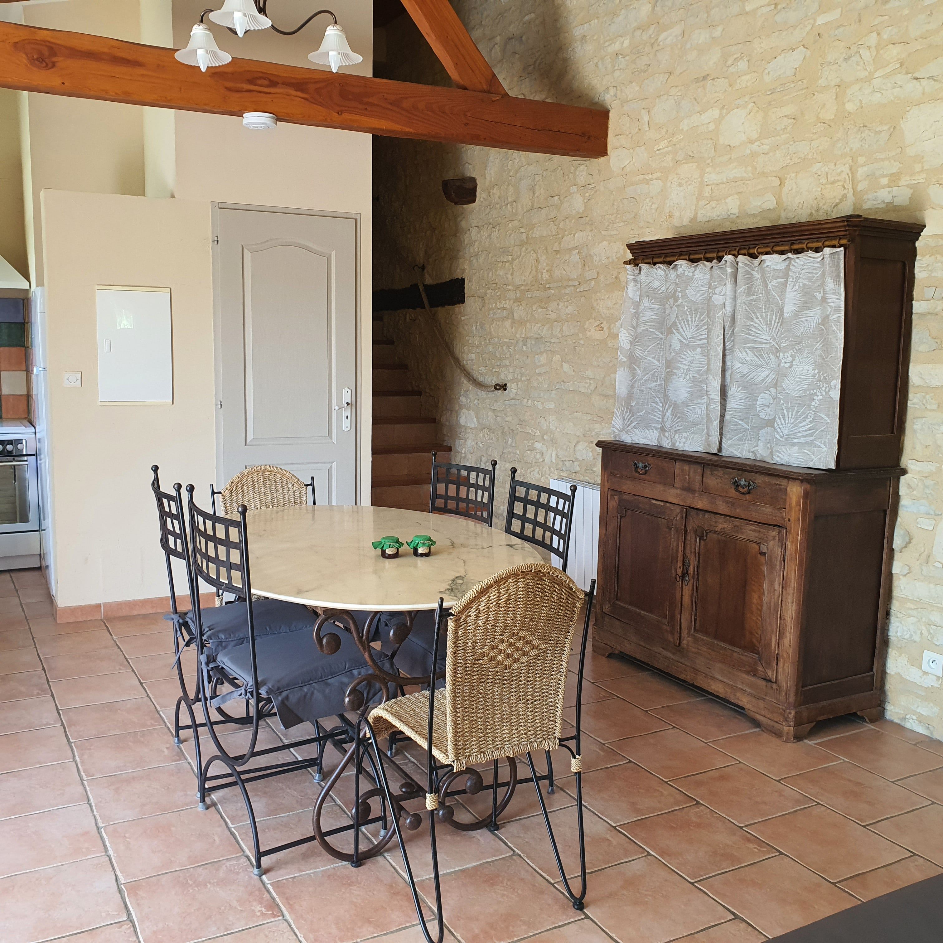 A dining area with a round table, chairs, and a cabinet.