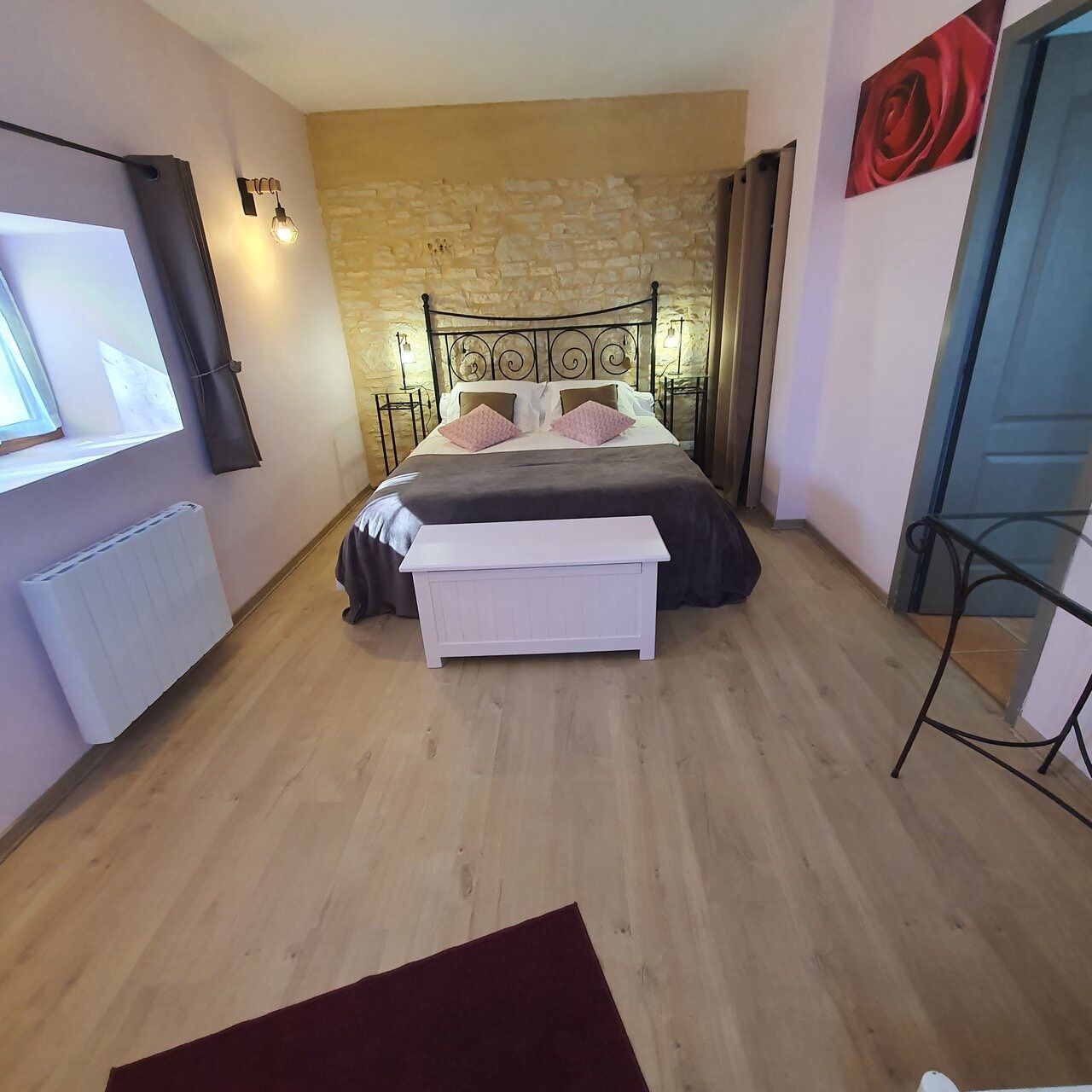 Une chambre à coucher avec un lit, des tables de chevet, un radiateur, une fenêtre et une porte.