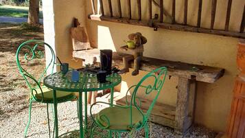 A patio with a metal table and chairs, a wooden bench, and a rustic wall.