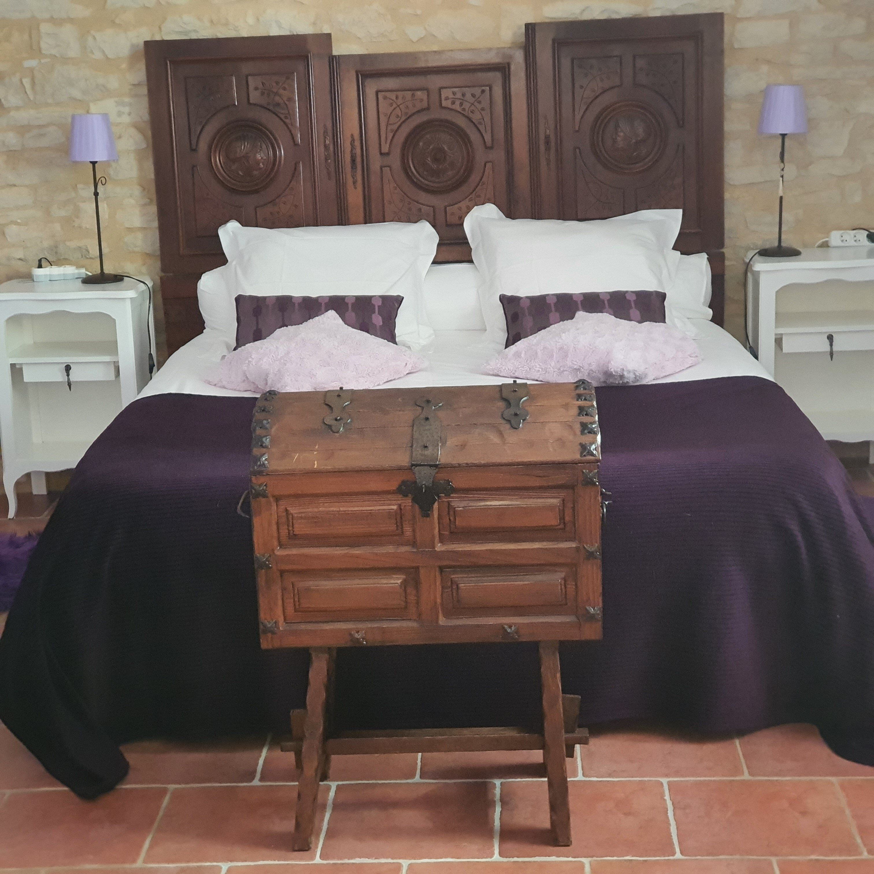 A bed with a wooden headboard, two bedside tables, and a small wooden chest in front.