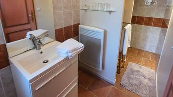 Een badkamer met een wastafel, spiegel, handdoekhouder en douche.