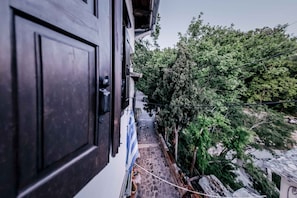 A narrow stone pathway leading to a building with a dark door. - "Naida Superior Double" Room with Mountain View, Balcony, and Fireplace (Μακρινίτσα)