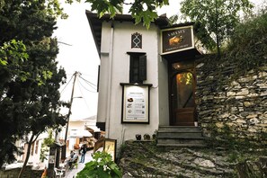 A building with a stone facade, a signboard, and a staircase leading to the entrance. - "Naida Superior Double" Room with Mountain View, Balcony, and Fireplace (Μακρινίτσα)