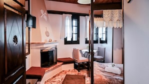 Een gezellige kamer met een open haard, een bed, een bureau en een stoel.