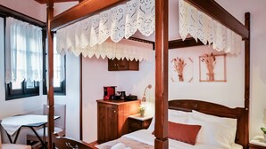 Un llit amb cortines i estructura de fusta, una taula de nit amb una làmpada, i una finestra amb cortines.