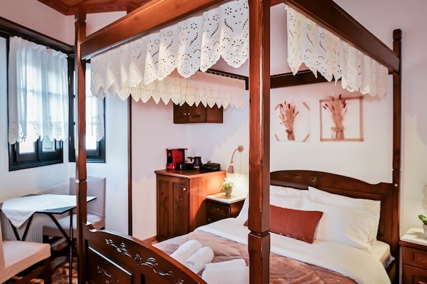 A four-poster bed with a wooden frame and white bedding, a bedside table with a lamp, and a window with curtains.