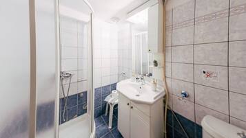 Een badkamer met een douche, wastafel en toilet.