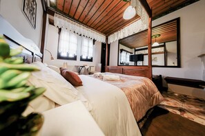 A hotel room with a wooden ceiling, a bed with white linens, a small table with a lamp, and a television. - "Arethousa Cozy Junior Suite" Room with Mountain View and Fireplace (Μακρινίτσα)