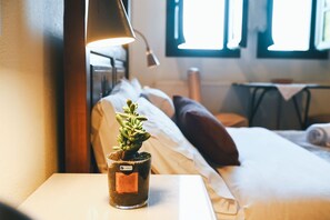 A hotel room with a bed, pillows, a bedside table with a potted plant, and a lamp. - "Arethousa Cozy Junior Suite" Room with Mountain View and Fireplace (Μακρινίτσα)