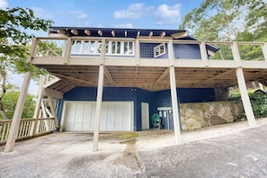 A two-story house with a garage, a covered porch, and a stone wall. - Glass Contemporary House, Panoramic Views, 4 Fireplaces, Game Room, Gym, Dog-Friendly (Highlands)