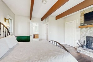 A bedroom with a large bed, a fireplace, and a staircase leading to another room. - Glass Contemporary House, Panoramic Views, 4 Fireplaces, Game Room, Gym, Dog-Friendly (Highlands)