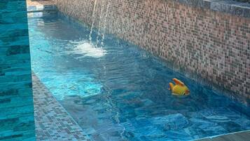 Une piscine avec une cascade et un jouet gonflable jaune.