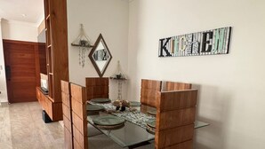 A dining area with a wooden dining table, cushioned chairs, and a decorative wall piece. - Welcome to Villa Sol y Mar, an ideal place for families and couples. (La romana)