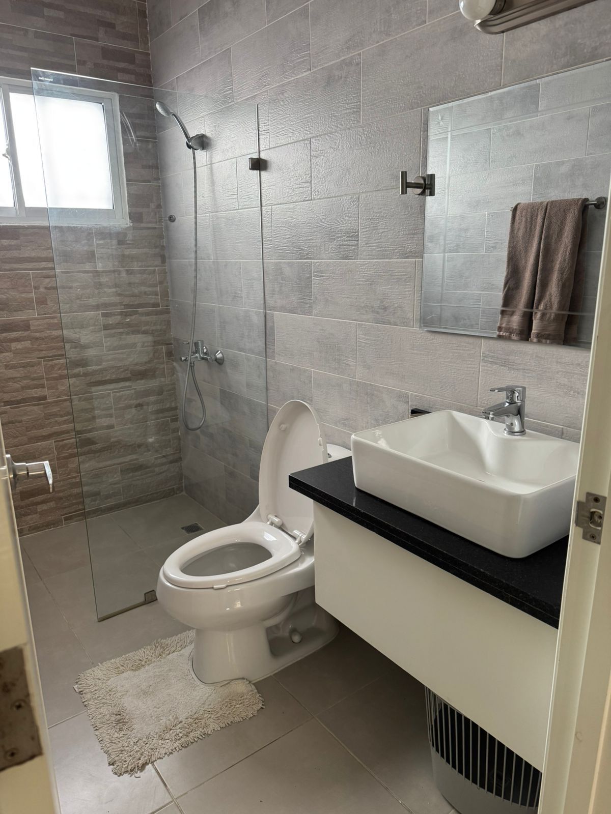 A modern bathroom with a shower, toilet, and sink.