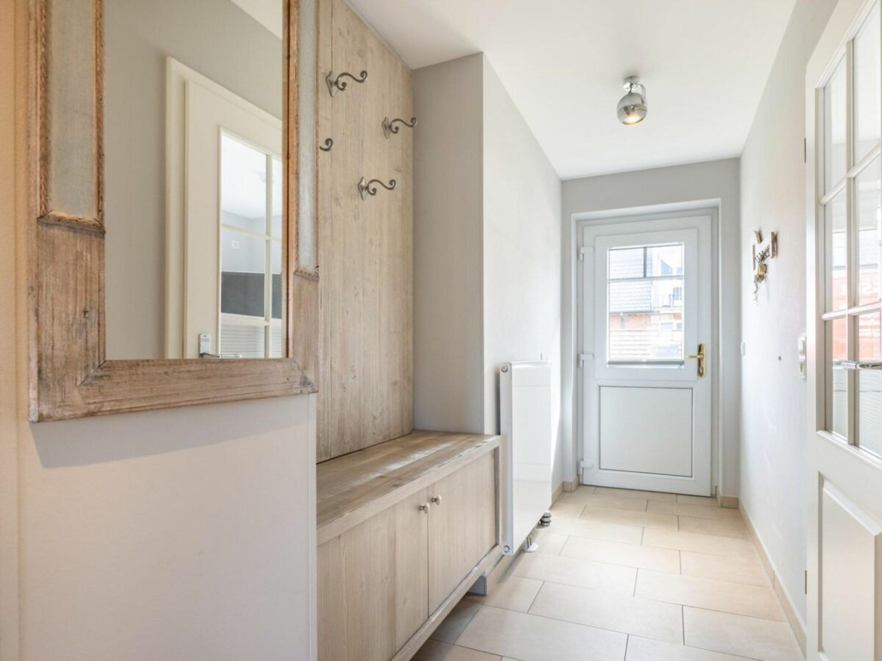 A hallway with a wooden cabinet, a radiator, and a white door.