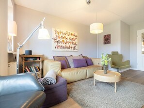Una sala moderna con sofá, sillón y una pequeña mesa redonda con un florero.