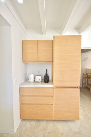 A compact kitchen with wooden cabinets, a countertop, and a built-in refrigerator. - Écrin Nature in Guéthary - Pool & Petanque (Guéthary)