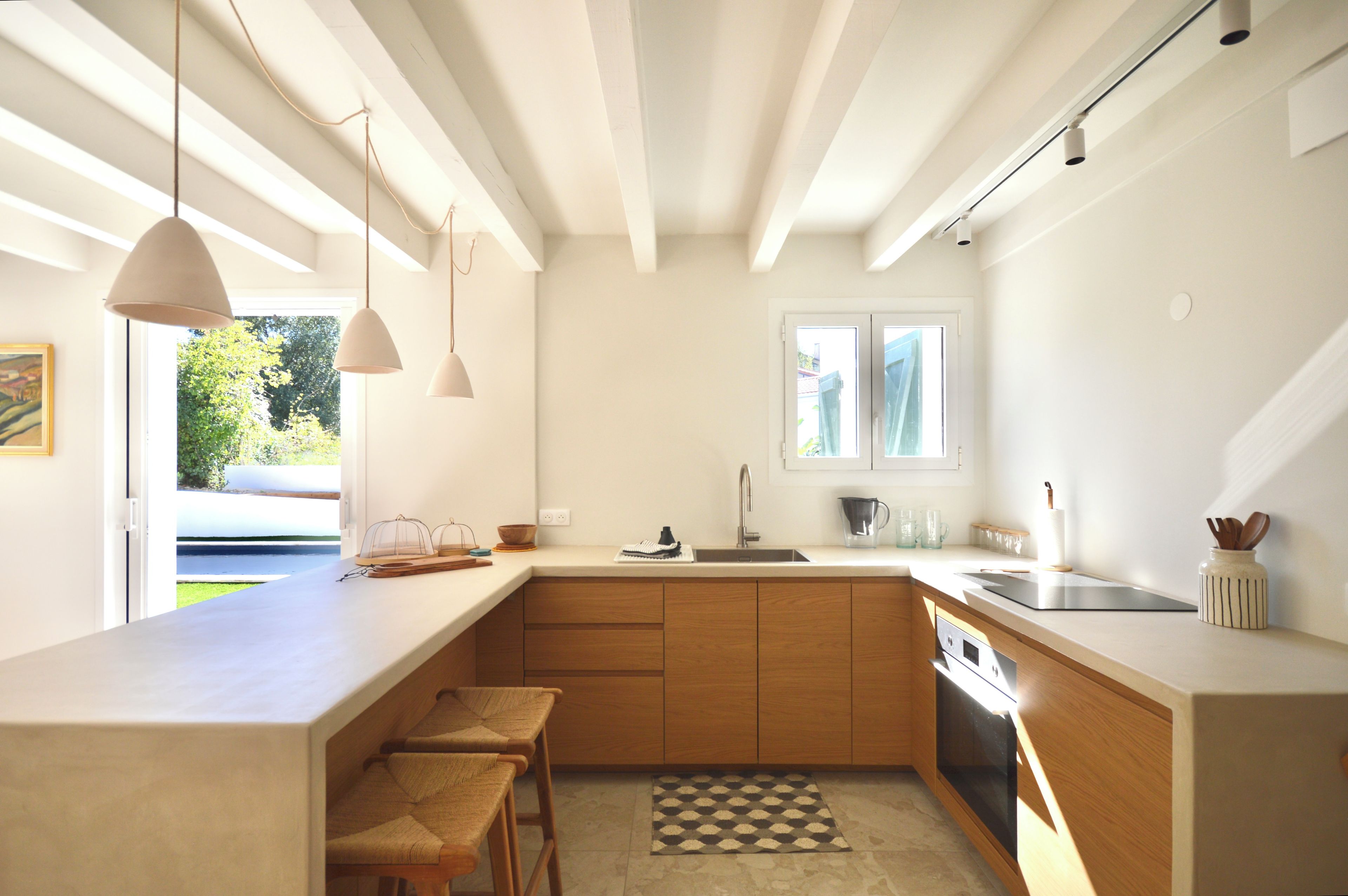 A modern kitchen with wooden cabinets, a built-in oven, and a large window providing natural light.