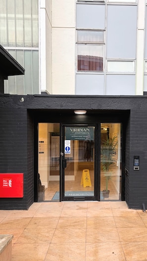 A building entrance with a sign for 'Viridian Apartments International House' and a 'Power Assisted door' sign. - International House by Viridian Apartments (London)