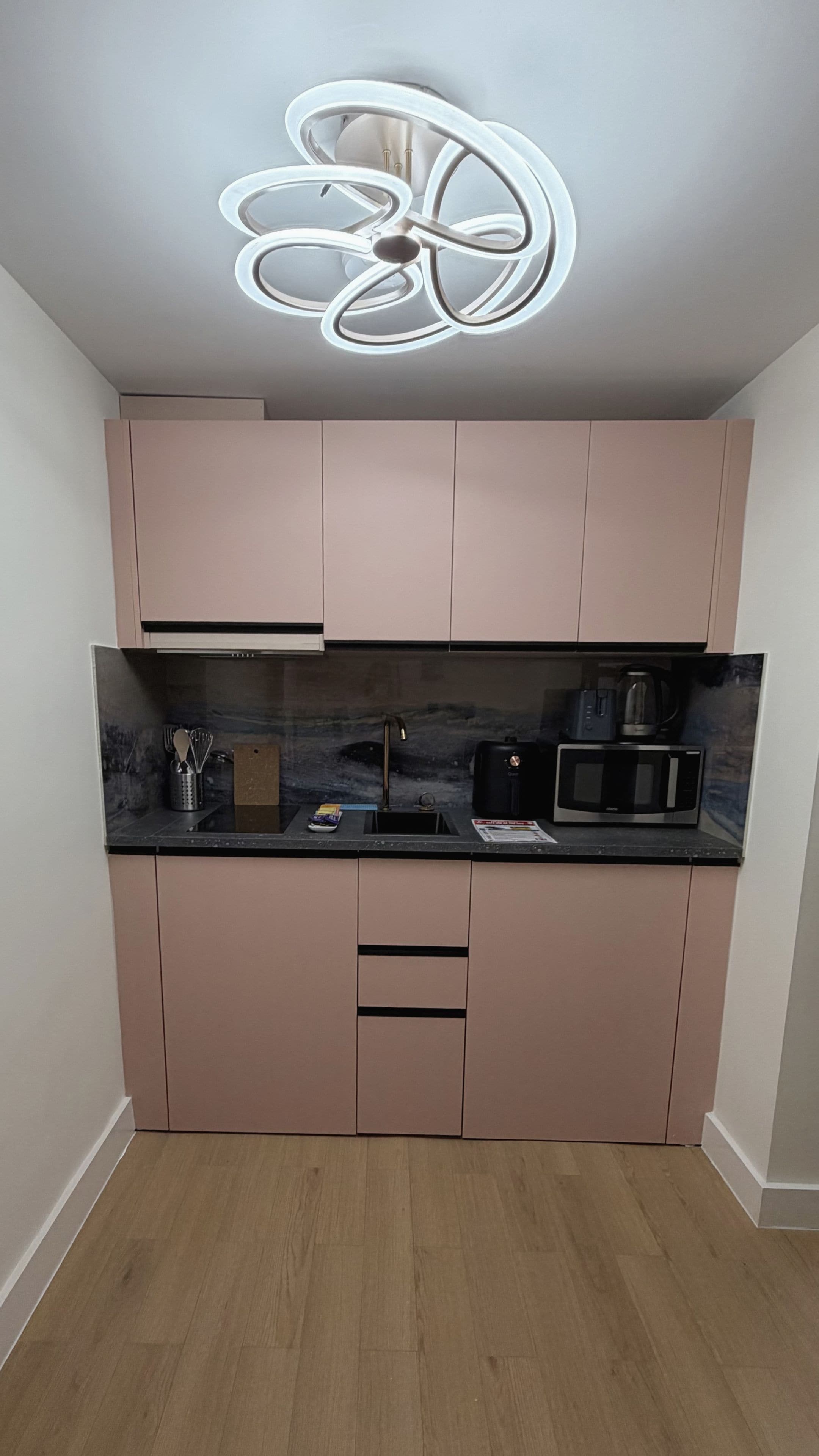 Una cocina moderna con microondas integrado, cafetera y pileta.