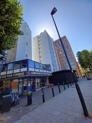 A building with a sign for a bicycle tour company, a street lamp, and a clear sky. - International House (London)