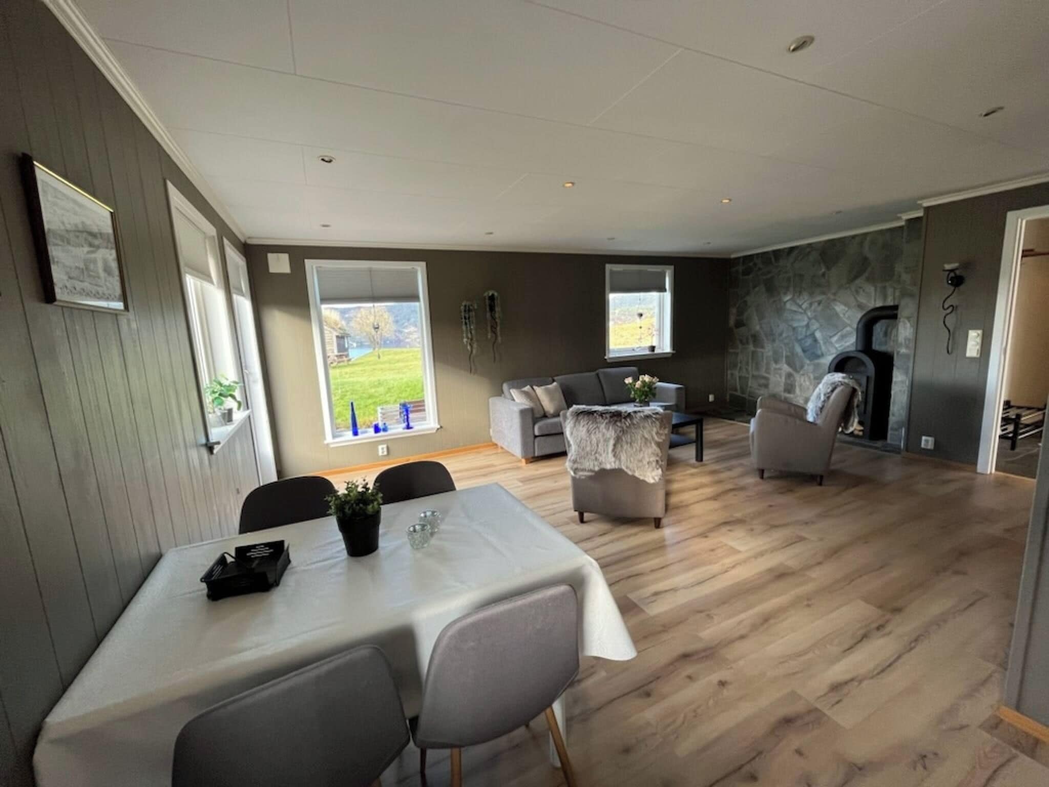 Un espacio habitable amplio con una mesa de comedor, sofás y una pared de piedra.