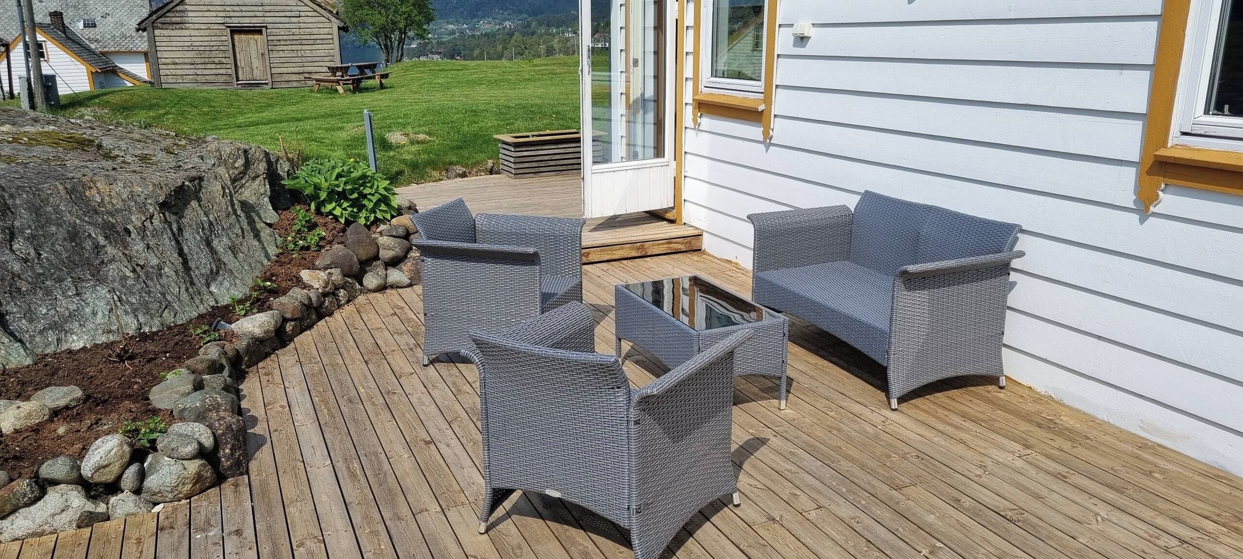 A deck with wicker furniture and a view of a house.