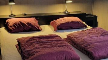 A double bed with a headboard, two bedside lamps, and multiple pillows.