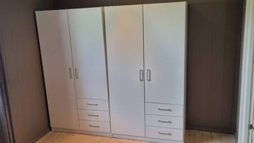 Un armario grande con varias puertas y cajones, situado en una habitación con suelo de madera y un ventanal.