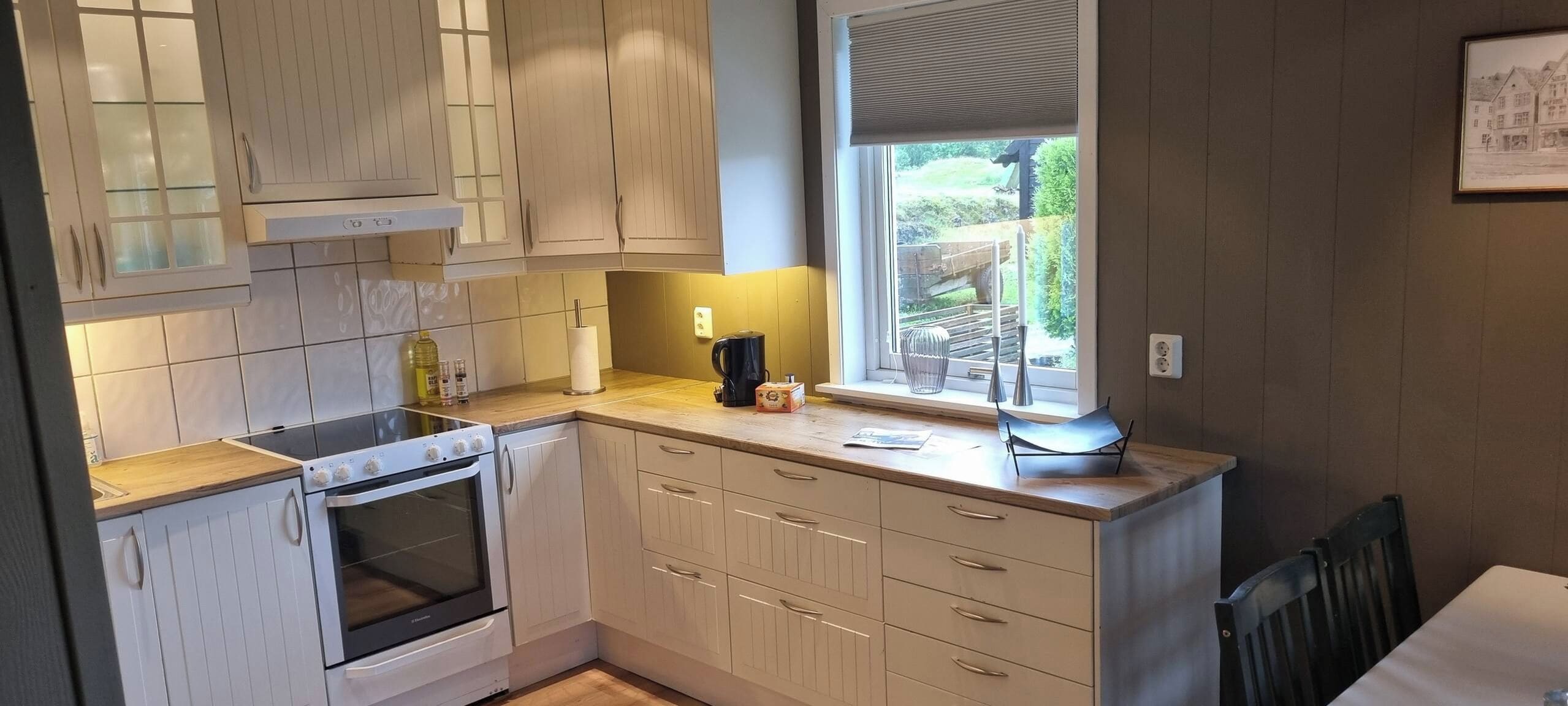 A kitchen with a built-in oven, a window with a view, and a dining area with a table and chairs.