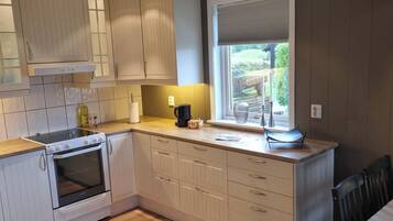 A kitchen with a built-in oven, a window with a view, and a dining area with a table and chairs.