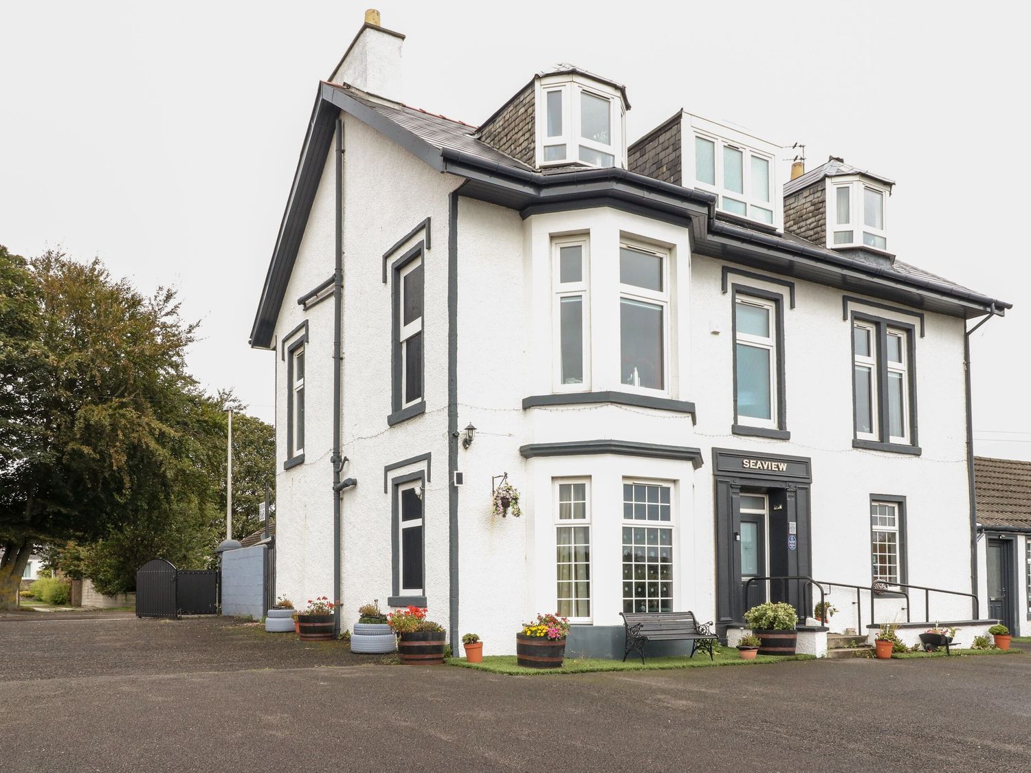 A two-story building with a white facade and black trim, featuring a prominent bay window and a sign that reads 'SEAVIEW'.