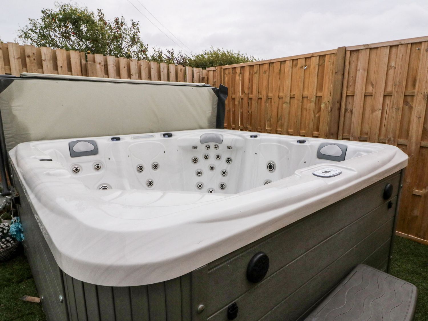 A hot tub with a cover, a control panel, and a step leading up to it.