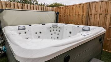 A hot tub with a cover, a control panel, and a step leading up to it.