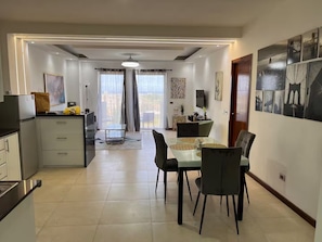 Un espacio habitable moderno con cocina, comedor y un amplio ventanal con cortinas.