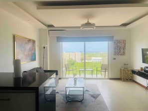Una sala moderna con sofá, una mesita de centro y vistas a un balcón con un paisaje urbano.