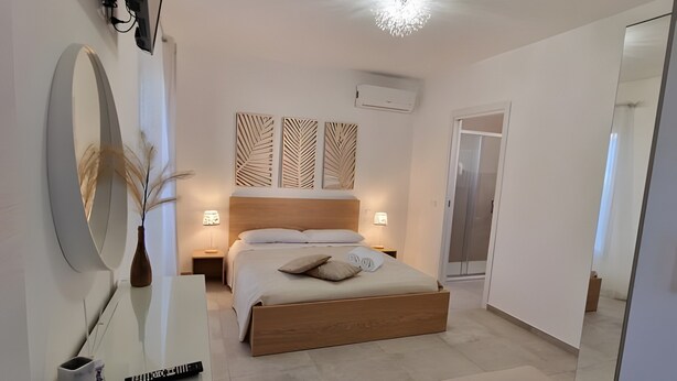 A modern bedroom with a bed, bedside tables, a mirror, and a wardrobe. - Room '1 - Villa Fragi' with Mountain View, Wi-Fi and Air Conditioning (Cinisi)