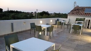 An outdoor patio area with tables and chairs, a white wall, and a tiled roof. - Room '1 - Villa Fragi' with Mountain View, Wi-Fi and Air Conditioning (Cinisi)