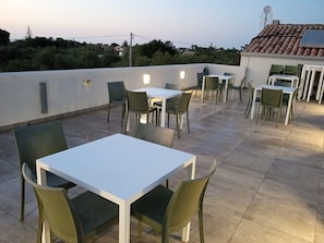 An outdoor patio area with tables and chairs, a white wall, and a tiled roof. - Room '1 - Villa Fragi' with Mountain View, Wi-Fi and Air Conditioning (Cinisi)