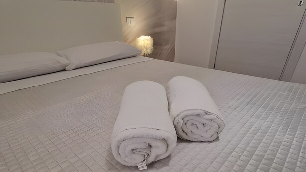 A bed with a quilted mattress and two rolled white towels placed on it. - Room '5 - Villa Fragi' with Mountain View, Wi-Fi and Air Conditioning (Cinisi)