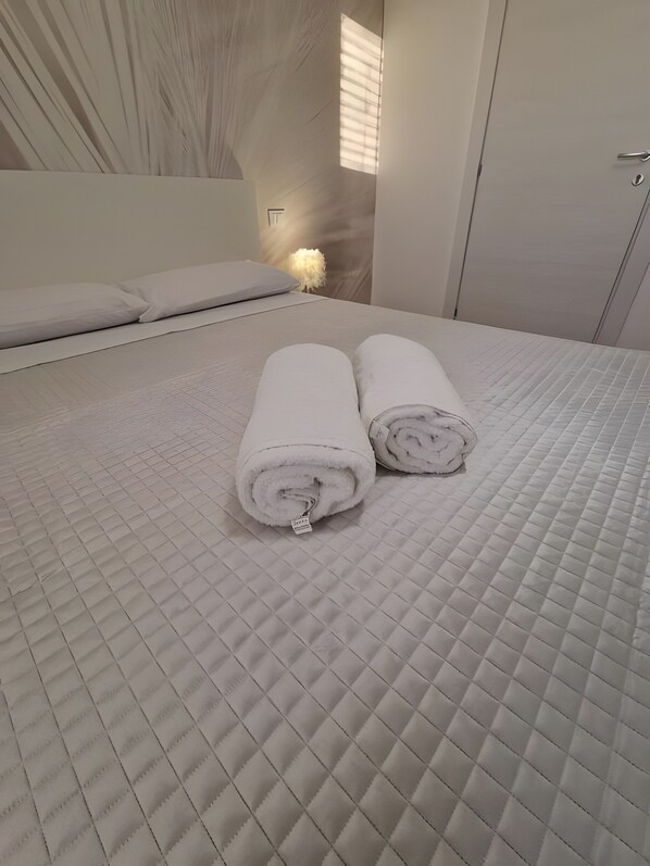 A bed with a quilted mattress and two rolled white towels placed on it. - Room '5 - Villa Fragi' with Mountain View, Wi-Fi and Air Conditioning (Cinisi)