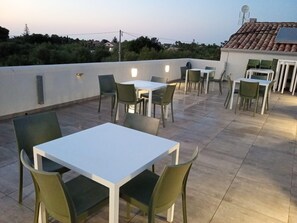An outdoor patio area with tables and chairs, a white wall, and a tiled roof. - Room '5 - Villa Fragi' with Mountain View, Wi-Fi and Air Conditioning (Cinisi)