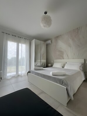 A modern bedroom with a large bed, a mirror, and a view of the outdoors. - Room '5 - Villa Fragi' with Mountain View, Wi-Fi and Air Conditioning (Cinisi)