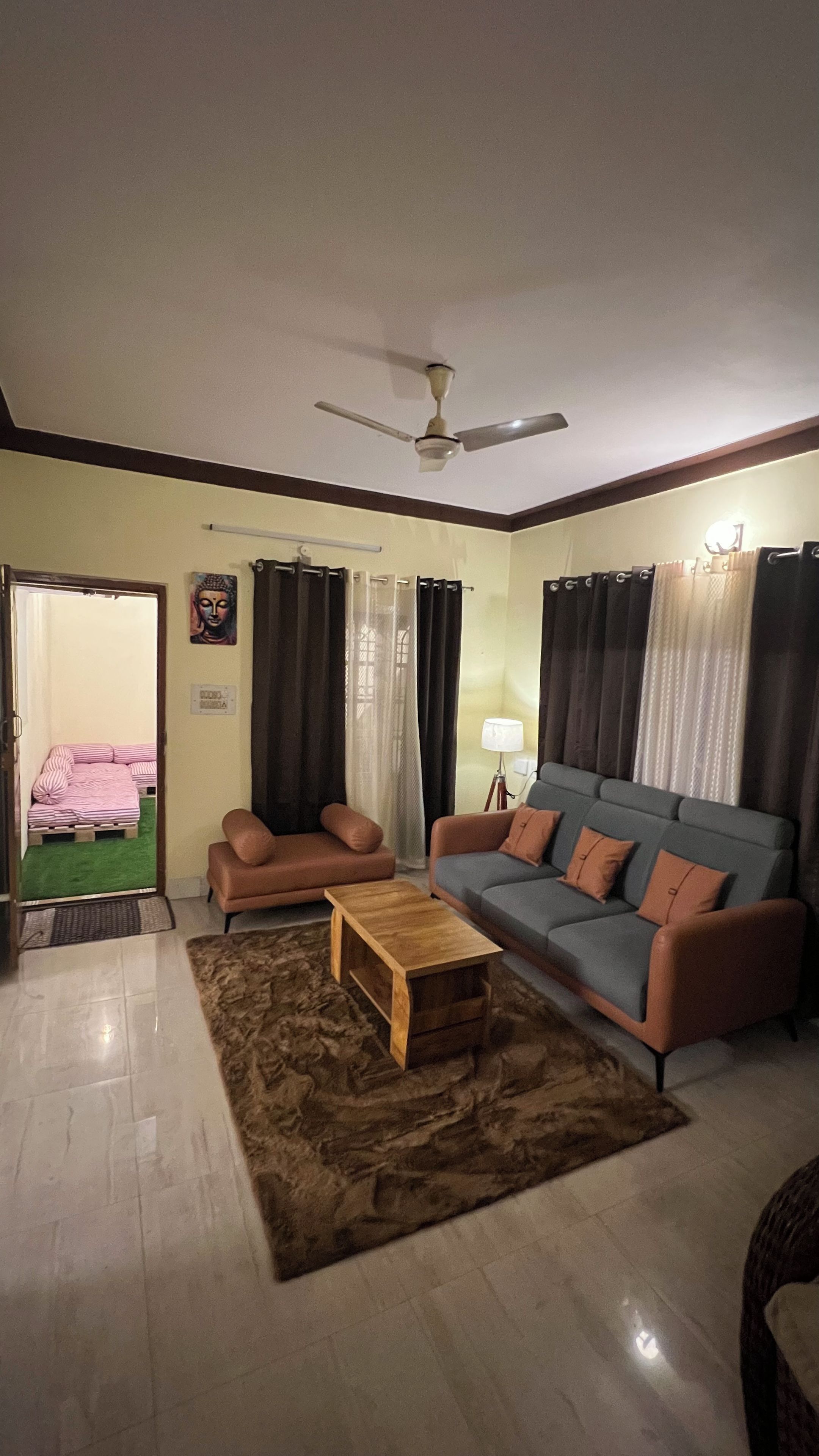 Un salon comprenant un canapé, deux fauteuils, une table basse, un ventilateur de plafond et une lampe.